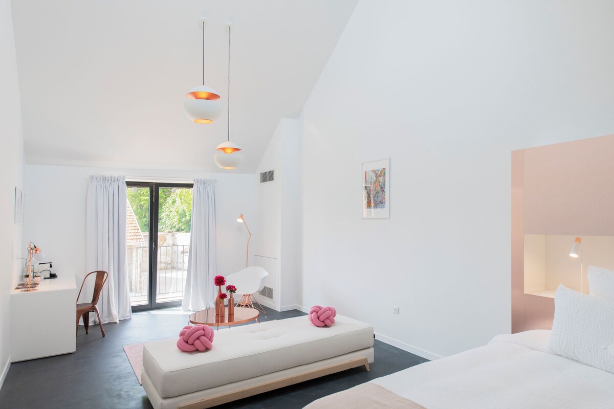 Une chambre d’hôtel moderne équipée d’un grand lit, d’un canapé, d’un bureau et d’un coin repas.