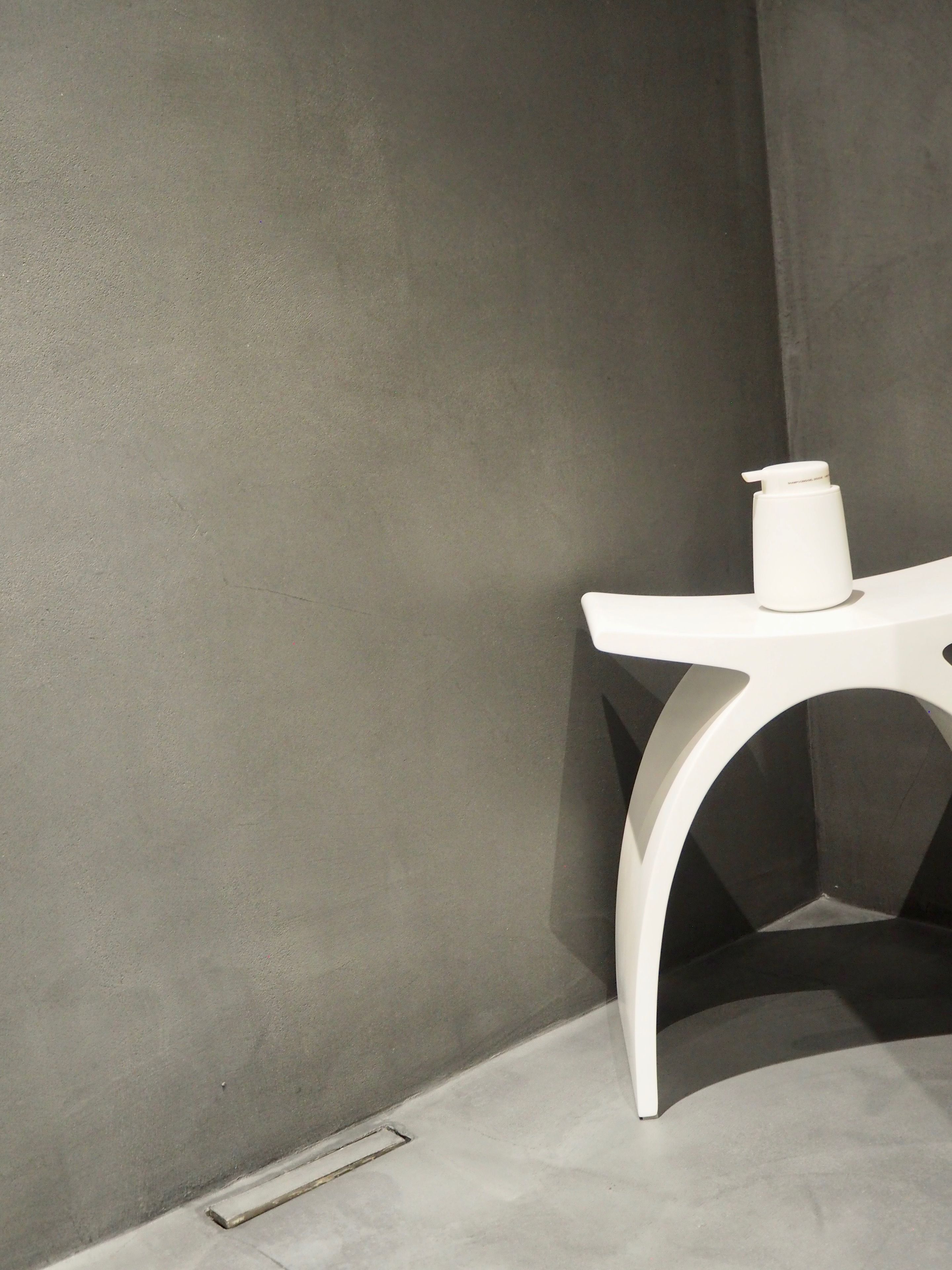 Una esquina de una habitación con una mesa blanca y un recipiente blanco encima.