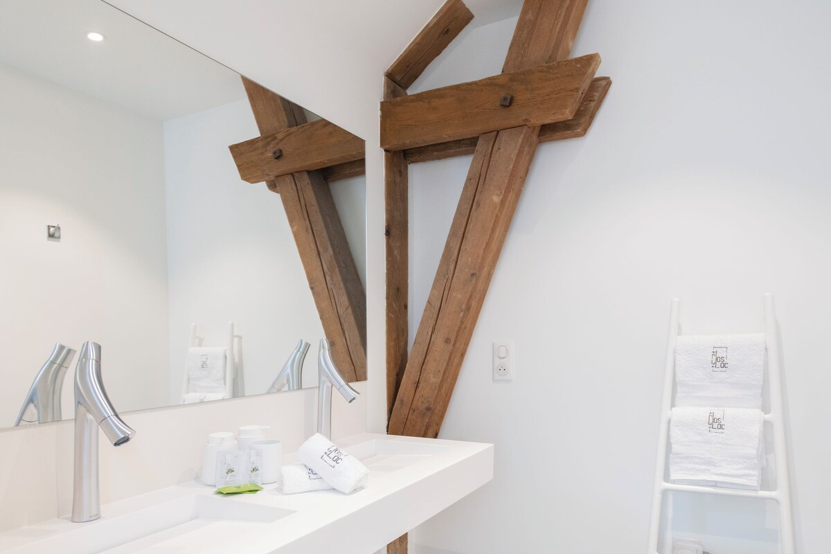 Un baño moderno con tocador blanco, dos lavamanos y un espejo grande.