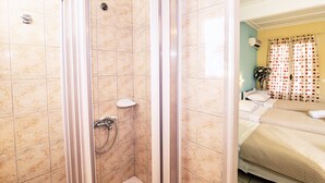 Habitación de hotel con ducha, cama y ventana con cortinas.
