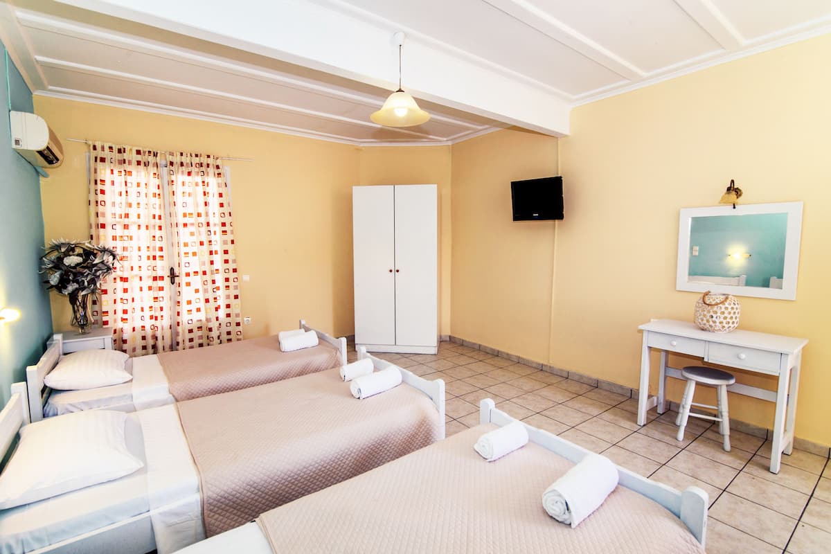 A hotel room with two beds, a desk, a TV, and a wardrobe.