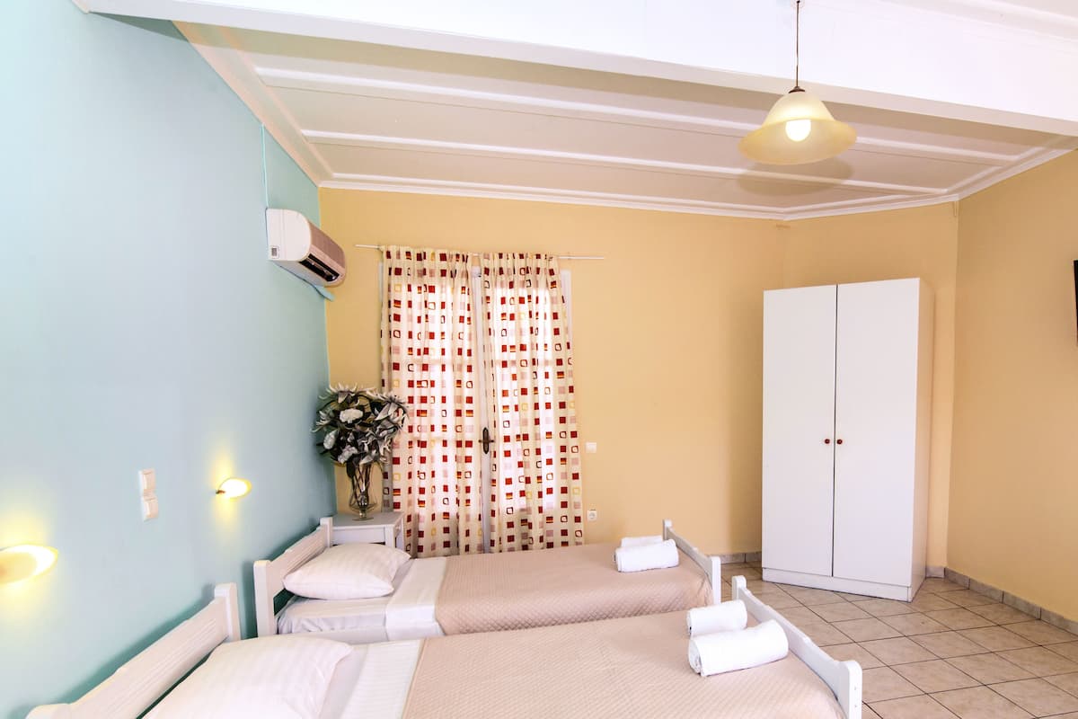 A hotel room with two beds, a wardrobe, and a curtain with a geometric pattern.