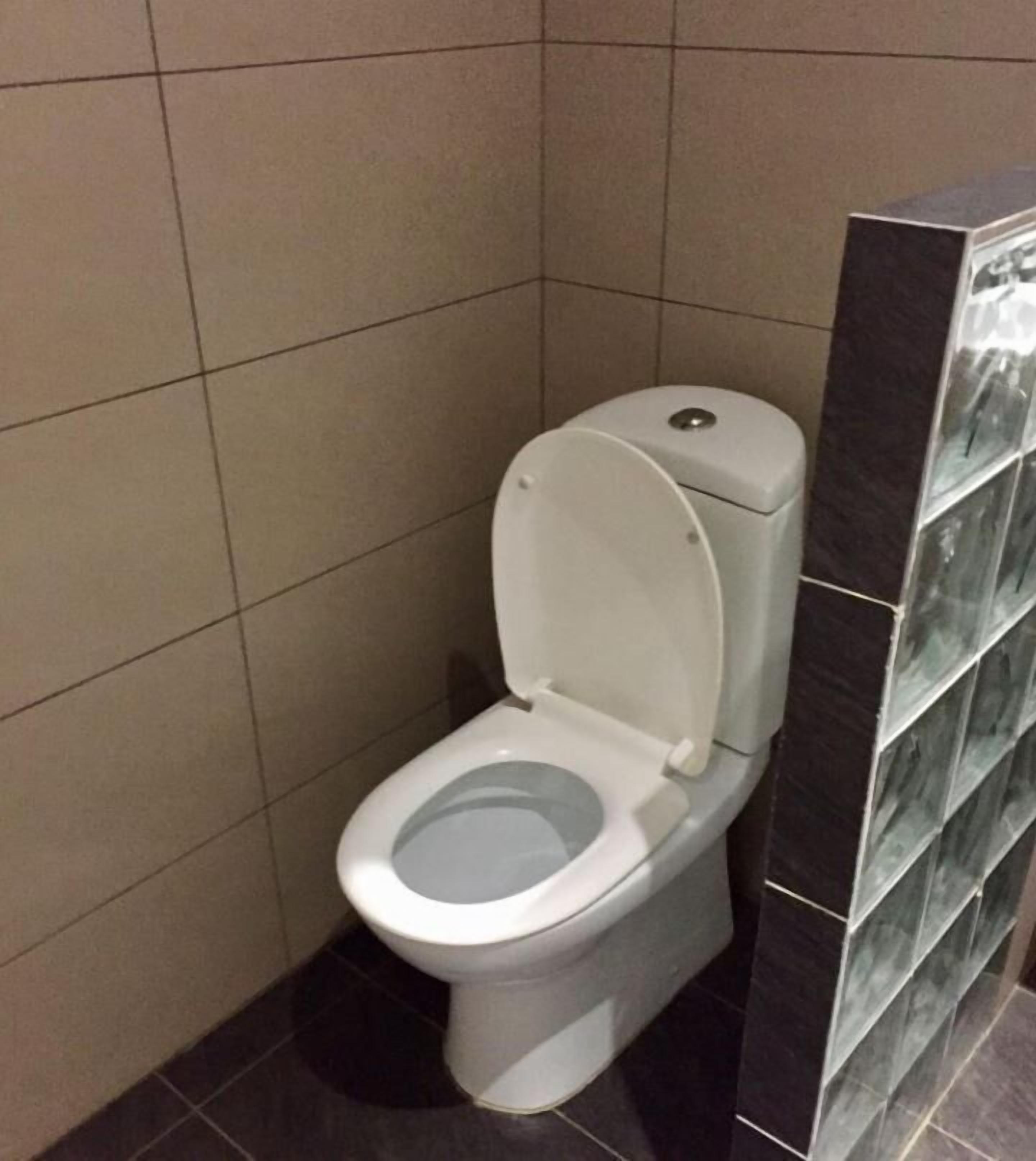 Een standaard toilet in een badkamer met betegelde wanden en vloer.