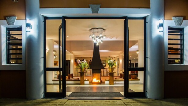 Una entrada de hotel con una chimenea central, un mostrador de recepción y un diseño interior moderno.