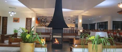 Un vestíbulo con chimenea central, zonas de estar y un bar.