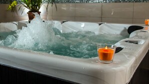 Un jacuzzi con agua salpicando, una vela y una planta en maceta.