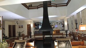 Un vestíbulo amplio con techo alto, chimenea central y zonas de estar.