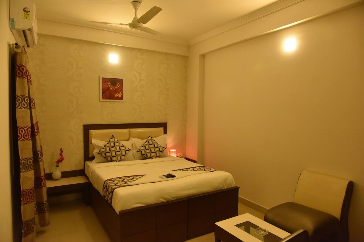 A neatly arranged bedroom with a bed, bedside table, chair, and a ceiling fan.