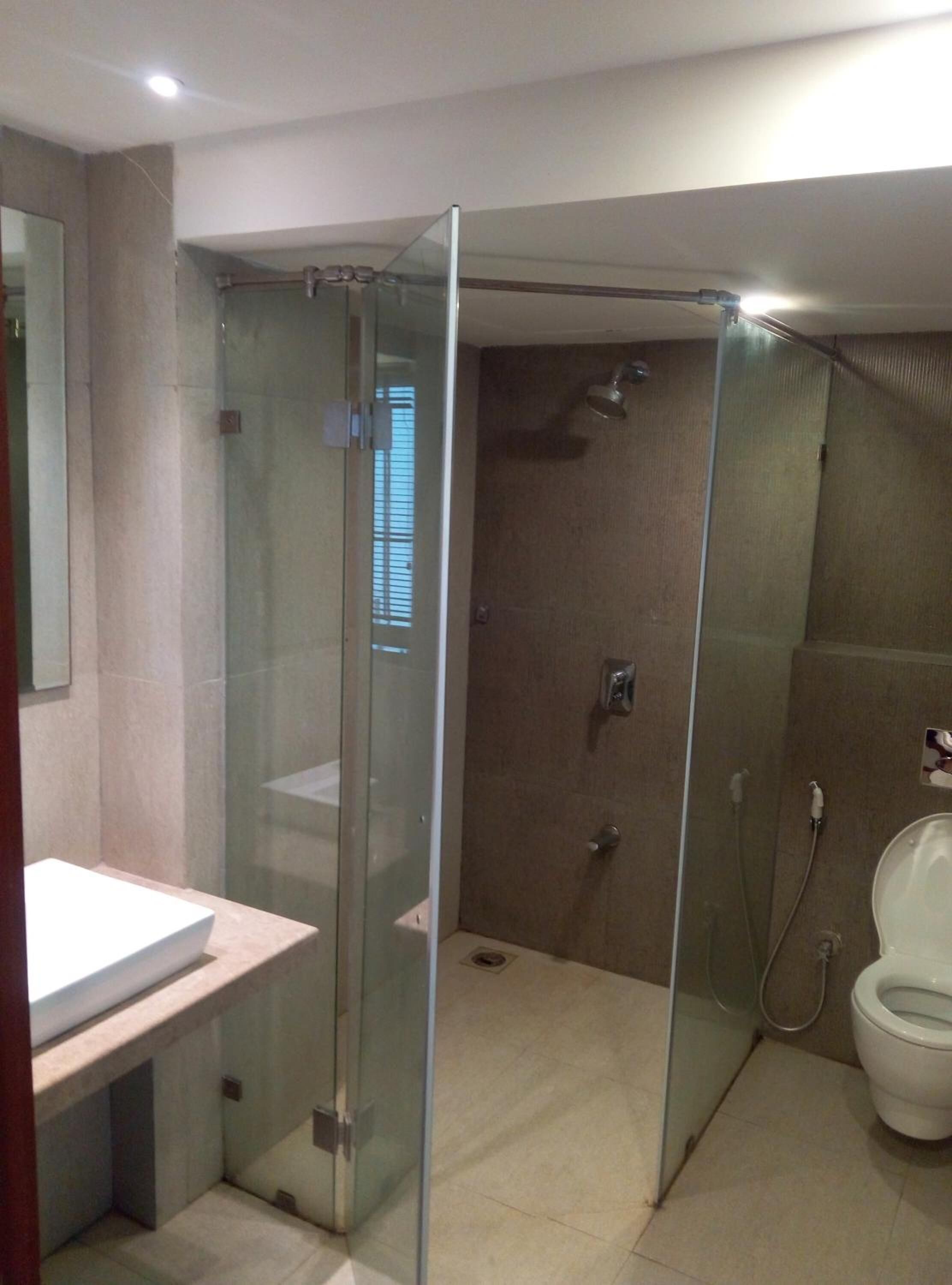 A modern bathroom with a glass-enclosed shower, a white sink, and a toilet.