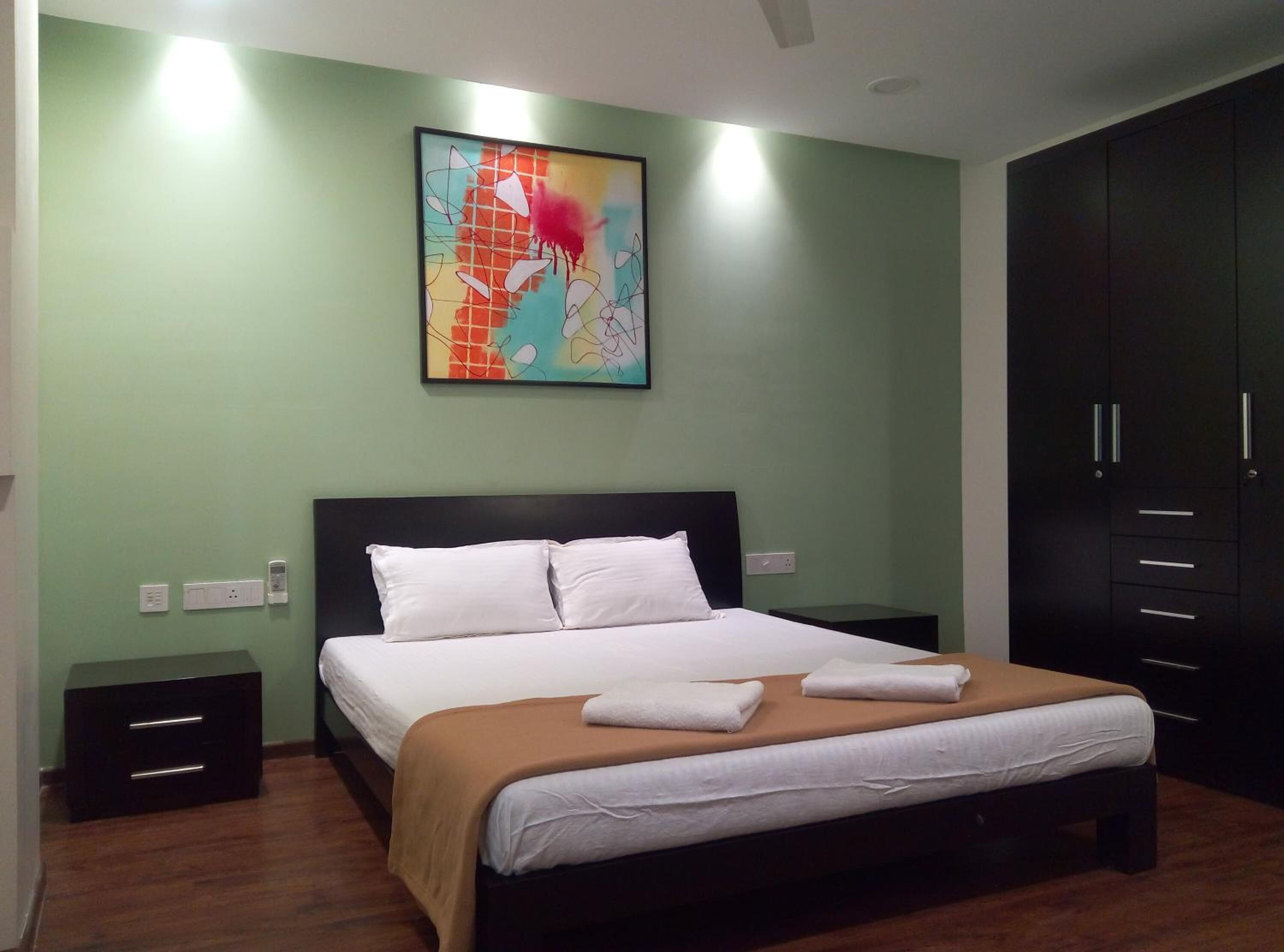 A bedroom with a bed, a nightstand, a wardrobe, and a painting on the wall.