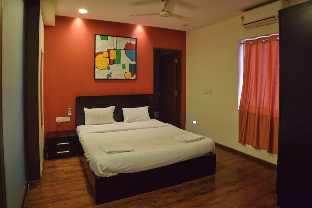 A bedroom with a bed, a ceiling fan, a painting on the wall, and a window with curtains.