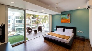 A modern hotel room with a large bed, a balcony with wicker chairs, and a view of the outside. - The Eternal Wave by Krish Retreat (Calangute)