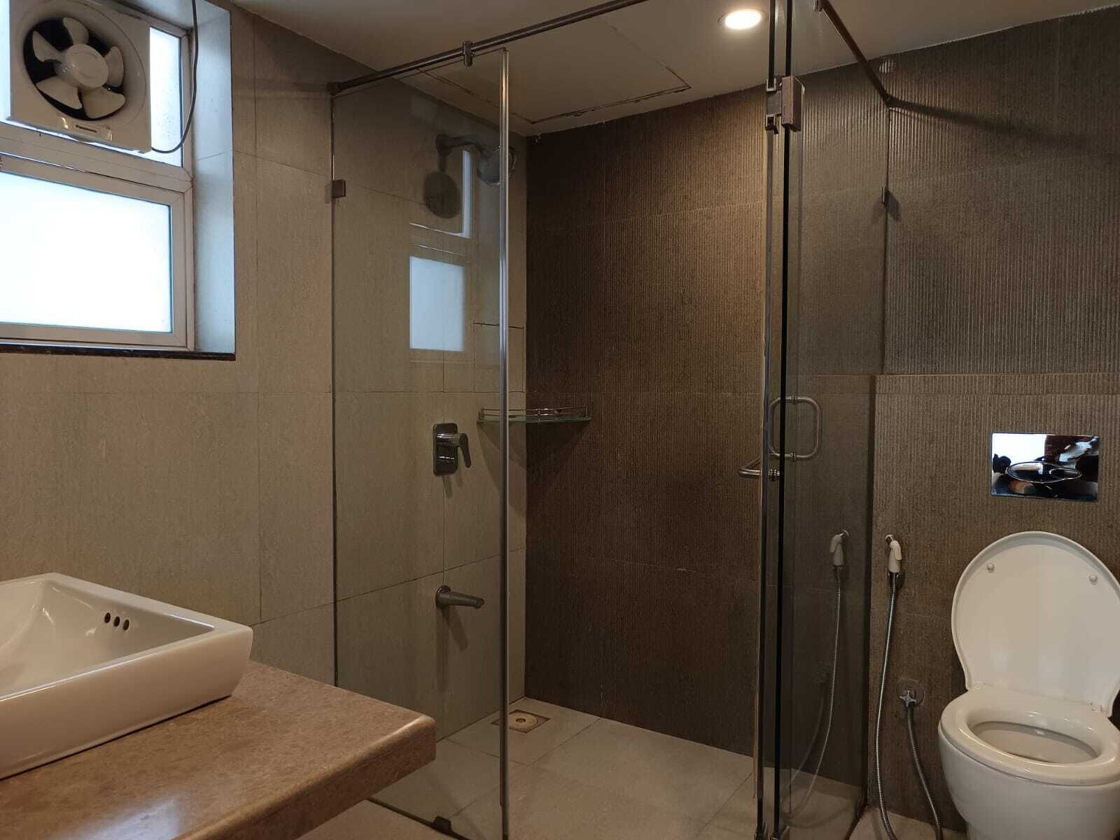 A modern bathroom with a glass-enclosed shower, a white sink, and a toilet.