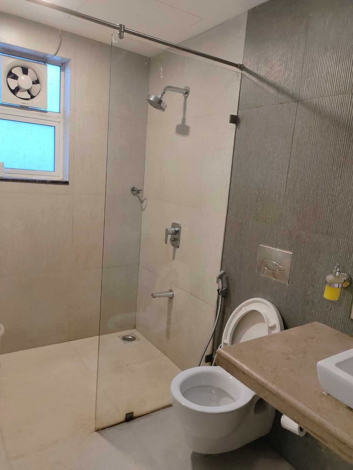 A small bathroom with a shower, toilet, and a window with a fan.