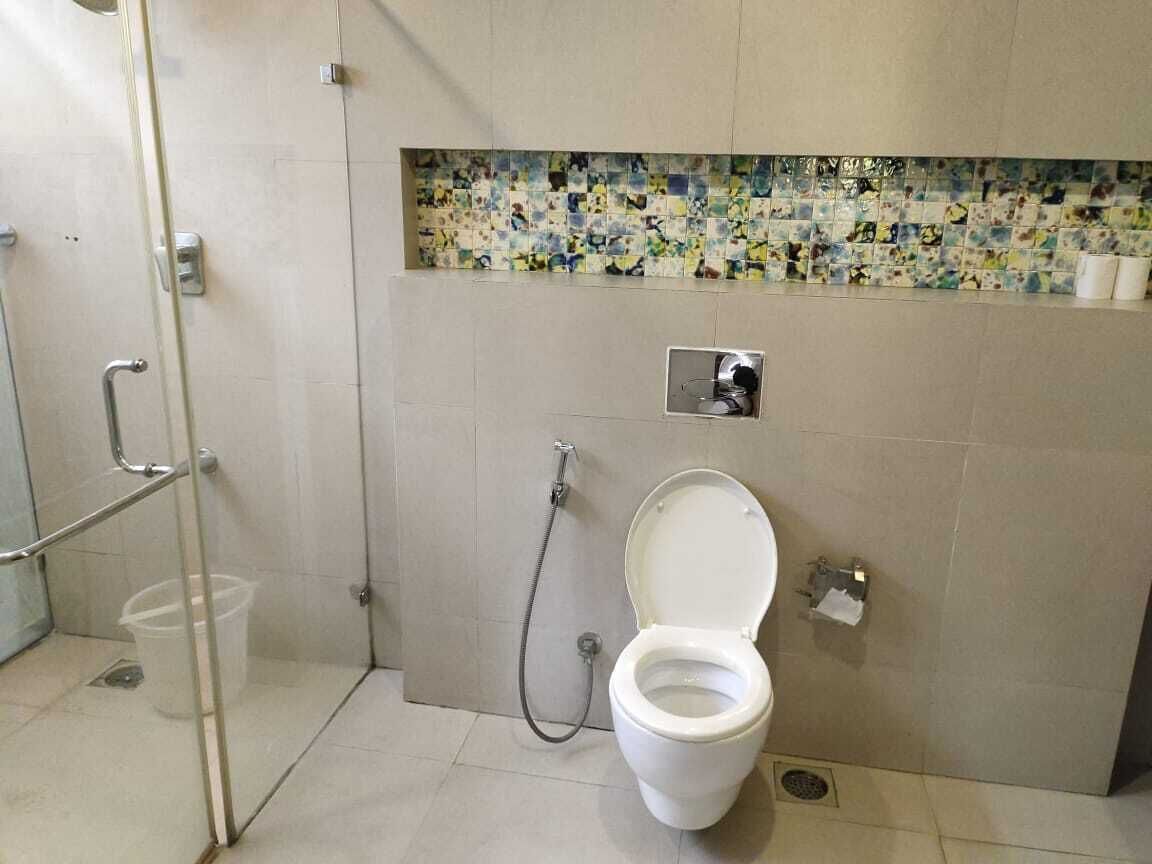 Un baño con inodoro, ducha y mampara de vidrio.