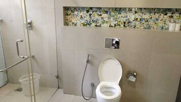 Un baño con inodoro, ducha y mampara de vidrio.