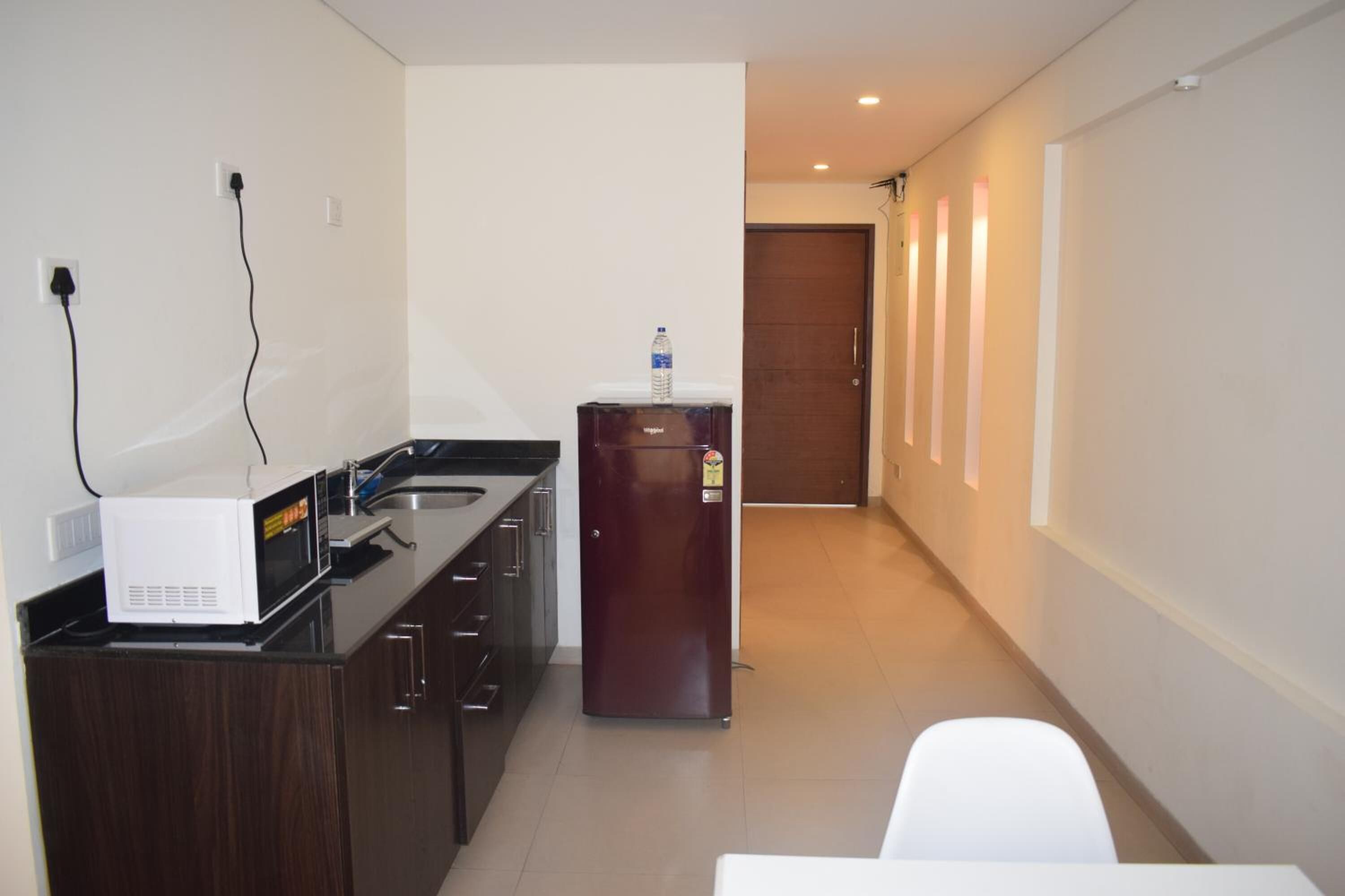 A compact kitchen with a microwave, refrigerator, and a water bottle on the counter.