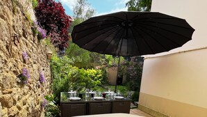 A hot tub with a table set for dining, surrounded by lush greenery and a stone wall.