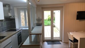 A modern kitchen with a built-in stove, a dining area with a table and chairs, and a sliding glass door leading to an outdoor patio.