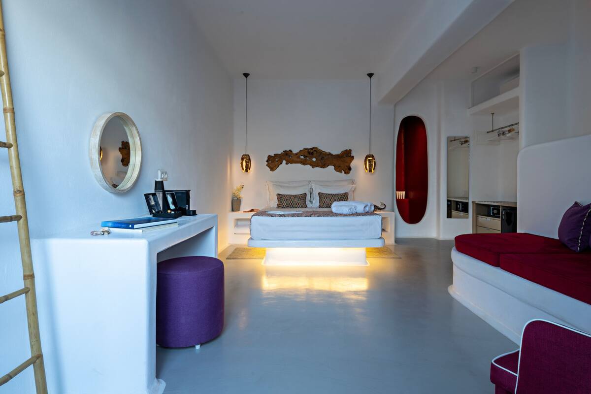 A modern bedroom with a bed, bedside table, and a desk with a chair.