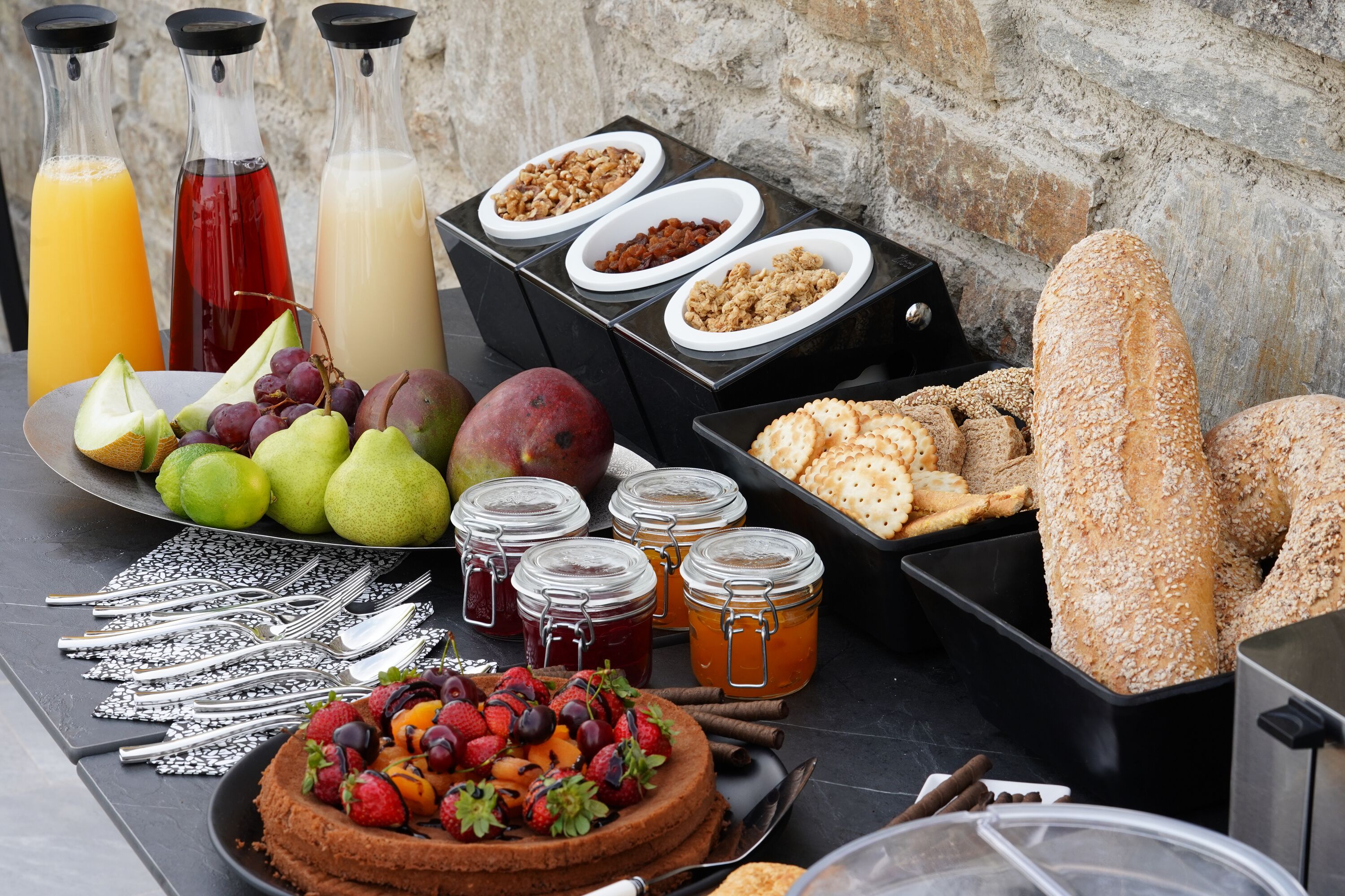 A breakfast buffet with various fruits, pastries, and beverages.