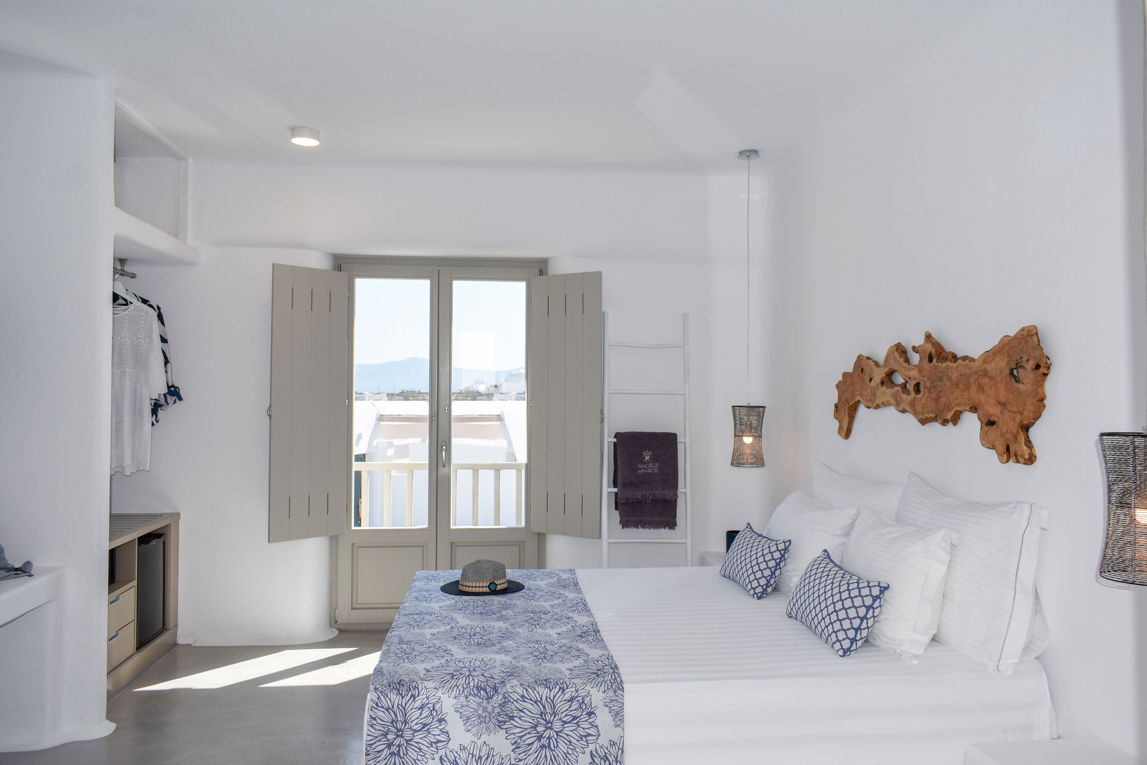 A bedroom with a bed, a wardrobe, a window, and a view of the city.
