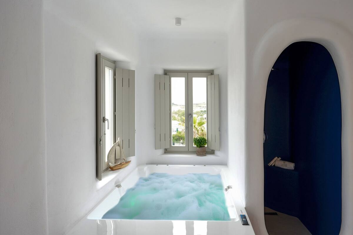 A bathroom with a bathtub, a window with a view, and a blue wall.