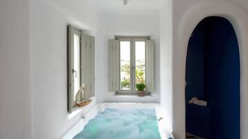A bathroom with a bathtub, a window with a view, and a blue wall.