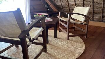 A rustic wooden dining area with two chairs, a woven mat, and a table.