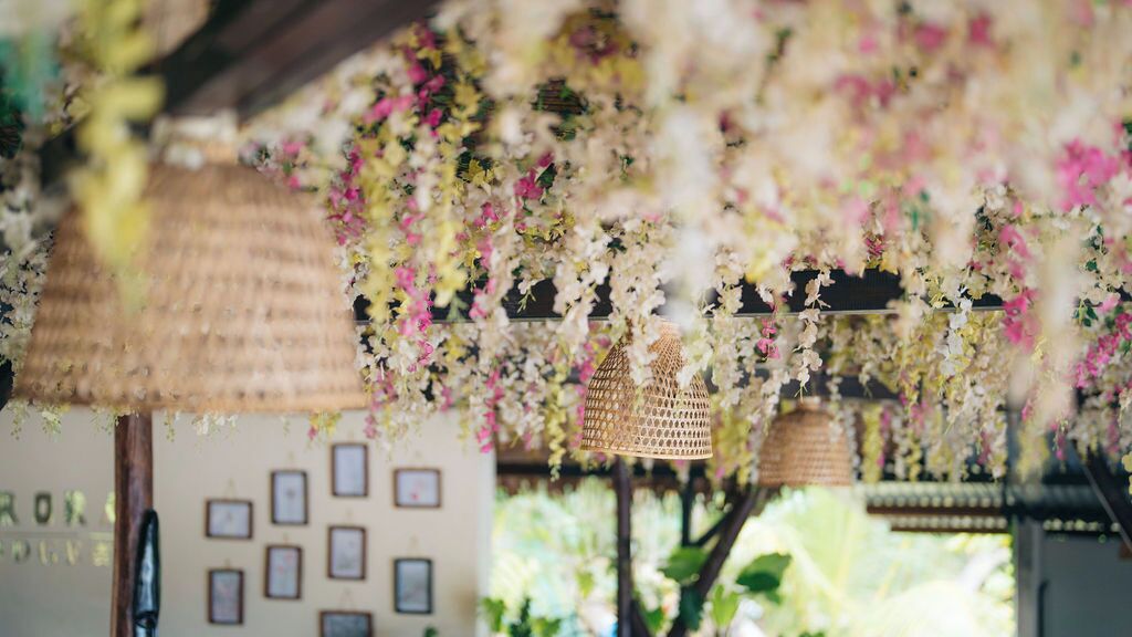 A room with a thatched roof, hanging floral decorations, and framed pictures on the wall.