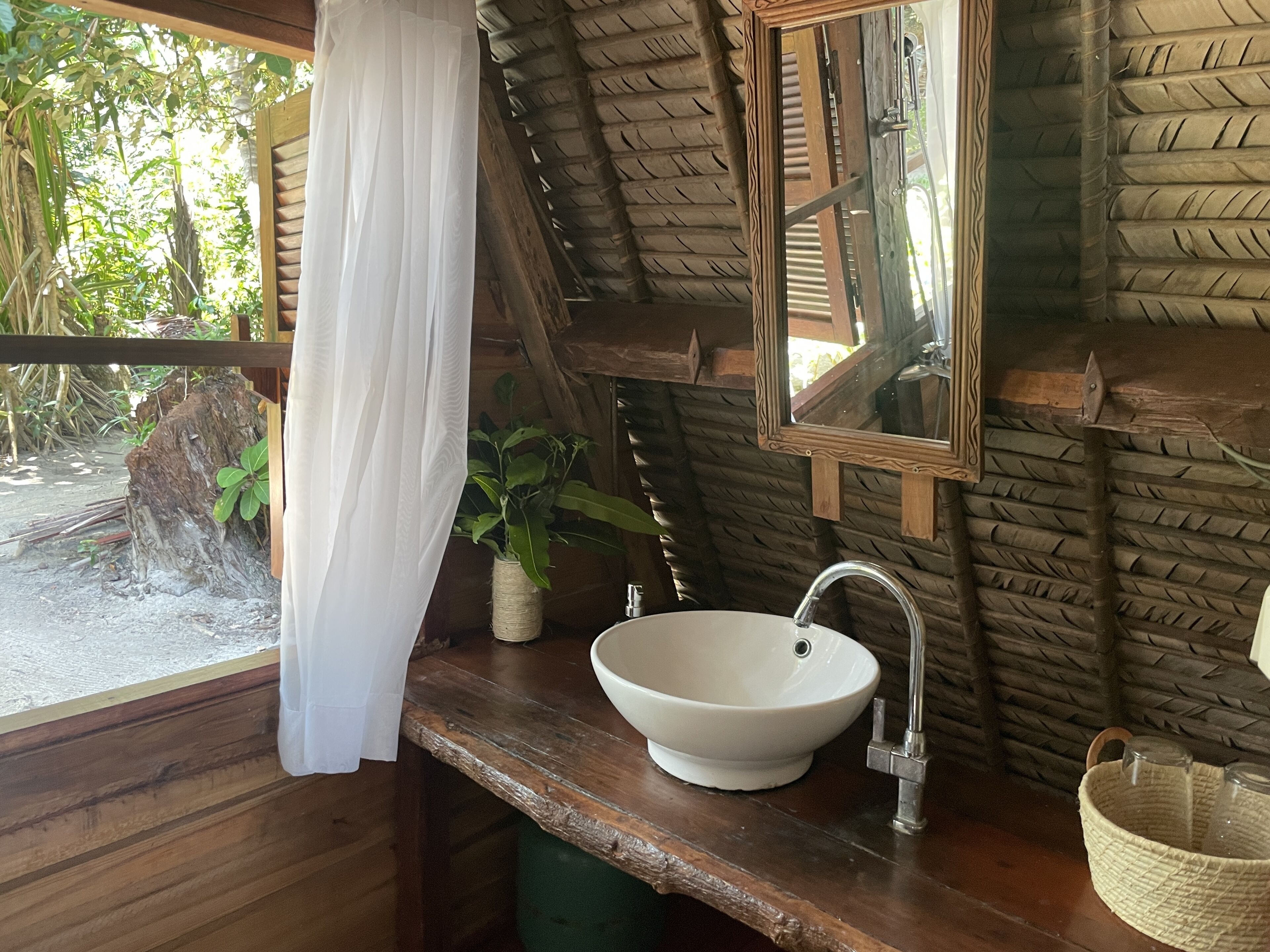 A rustic bathroom with a wooden ceiling, a white sink, and a mirror.