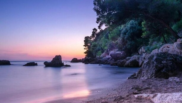 A coastal landscape with calm waters, rocky outcrops, and dense greenery. - Hotel Aurora (Minturno)