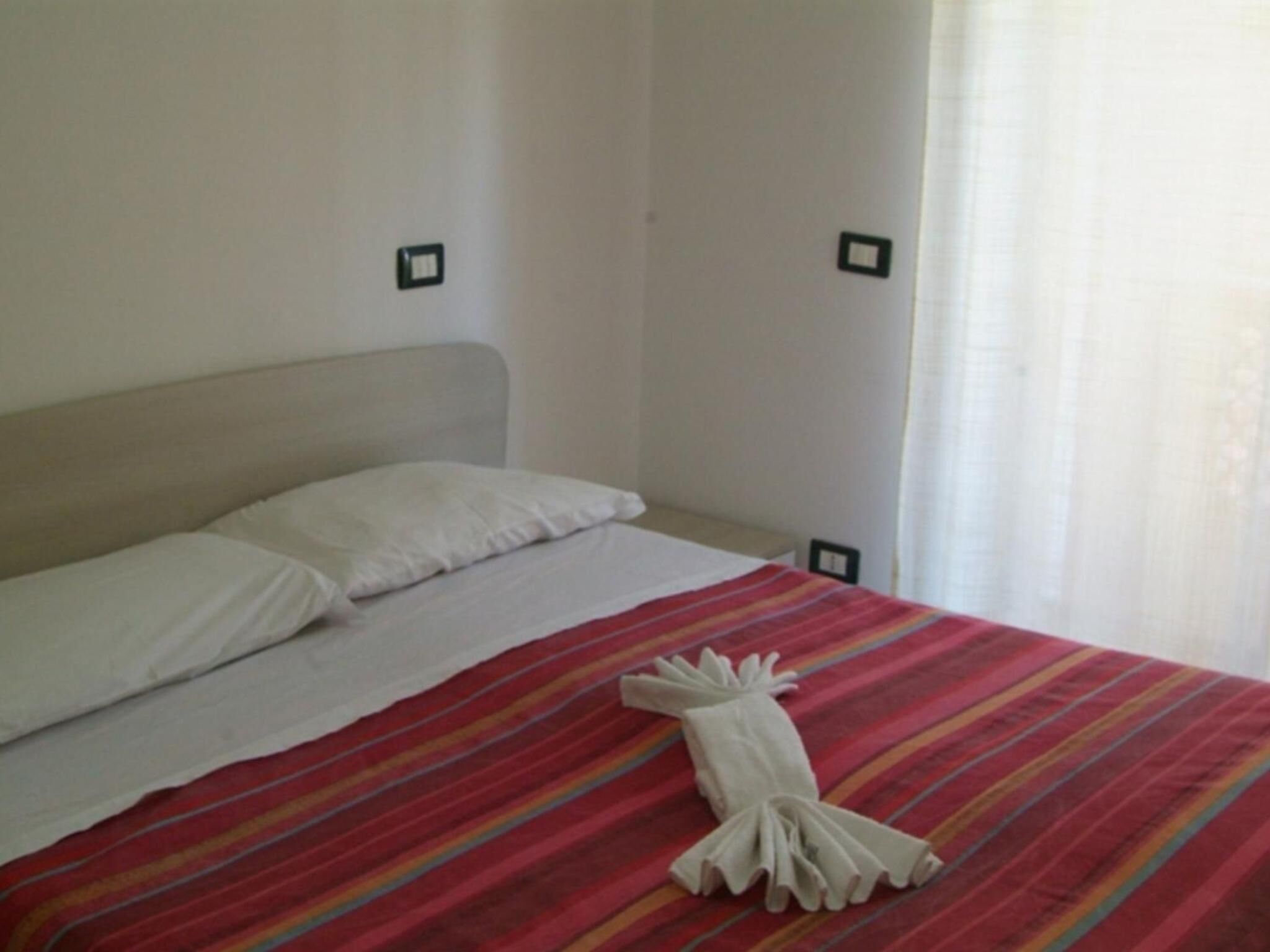 A neatly made bed with a striped bedspread and a folded towel.
