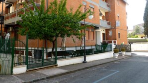 A multi-story residential building with balconies, a green fence, and a tree in front. - Hotel Aurora (Minturno)