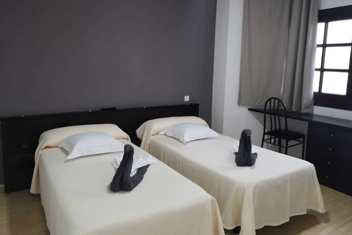 Una habitación de hotel con dos camas individuales, un escritorio y una silla.