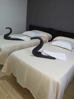 Two beds with white linens and black swan-shaped towels. - Hostal Asador Julian Brunete (Brunete)