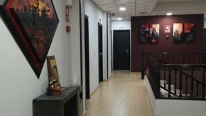 A hallway with a tiled floor, black doors, and a staircase with a black railing.