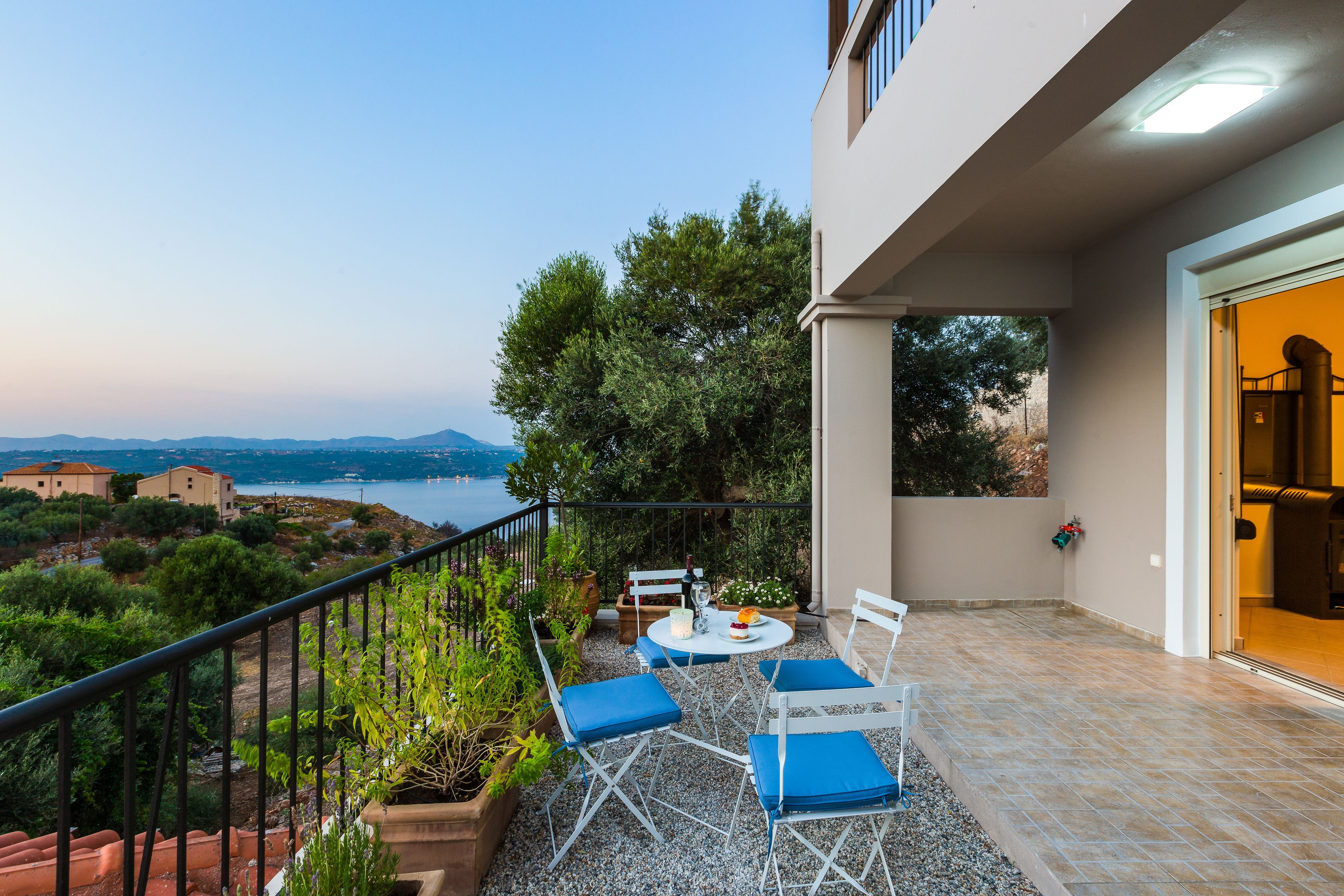 A balcony with a table and chairs, overlooking a scenic landscape with trees and a body of water.