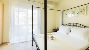 A neatly made bed with white linens, a tray with a croissant and a glass of water, and a framed picture of birds on the wall. - Villa Alysso (Chania)