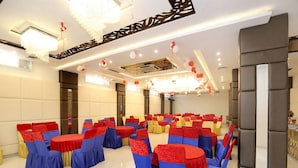 A banquet hall with round tables and chairs, red and blue tablecloths, and a chandelier. - Hotel Royal MJS Pinjore (Kalka)