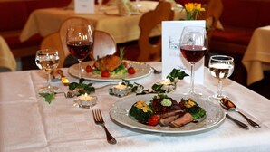 Une table à manger dressée avec des assiettes remplies de nourriture, des verres à vin et des bougies.