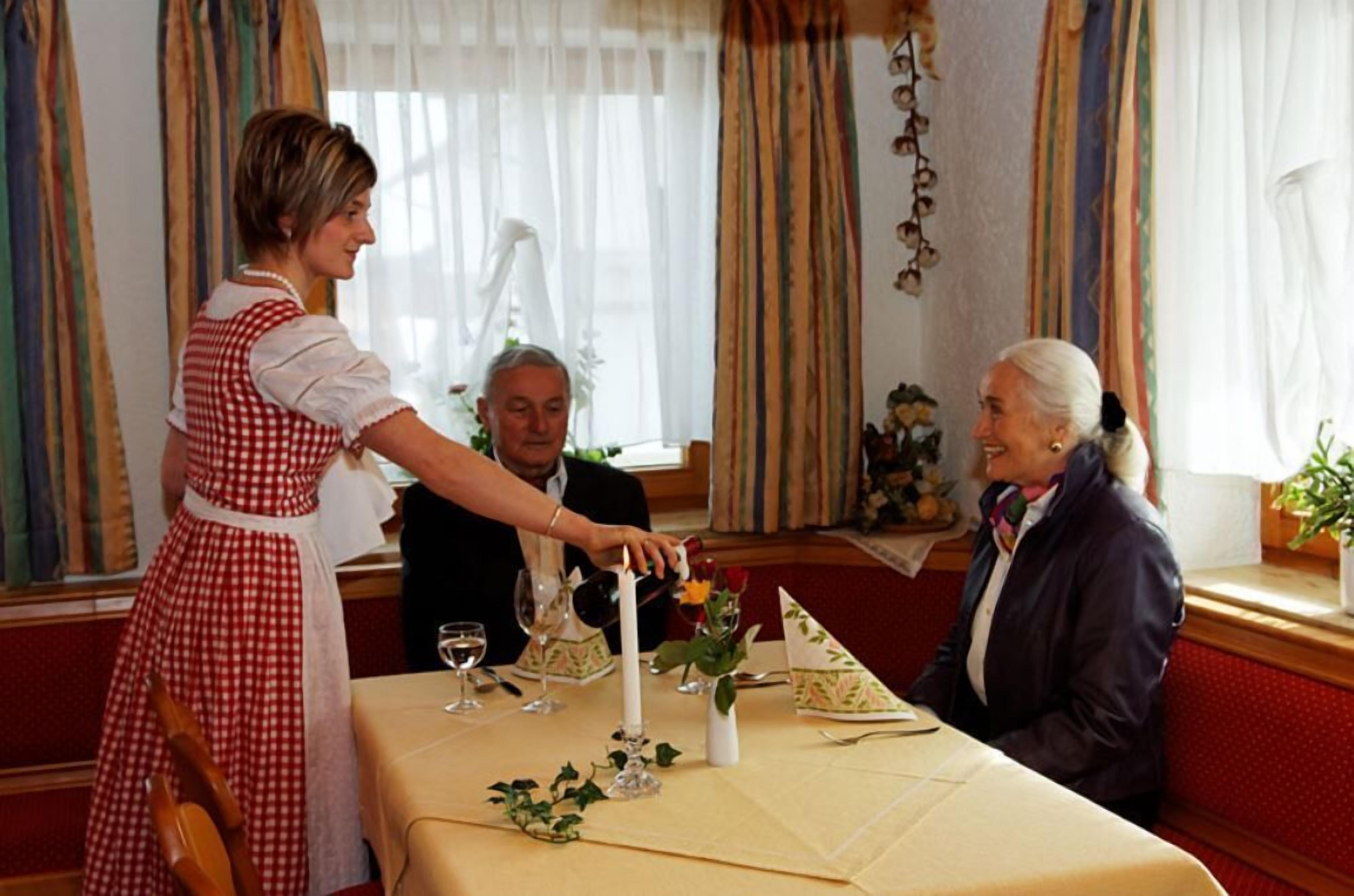Un comedor con una mesa dispuesta para dos, una vela y un jarrón con flores.
