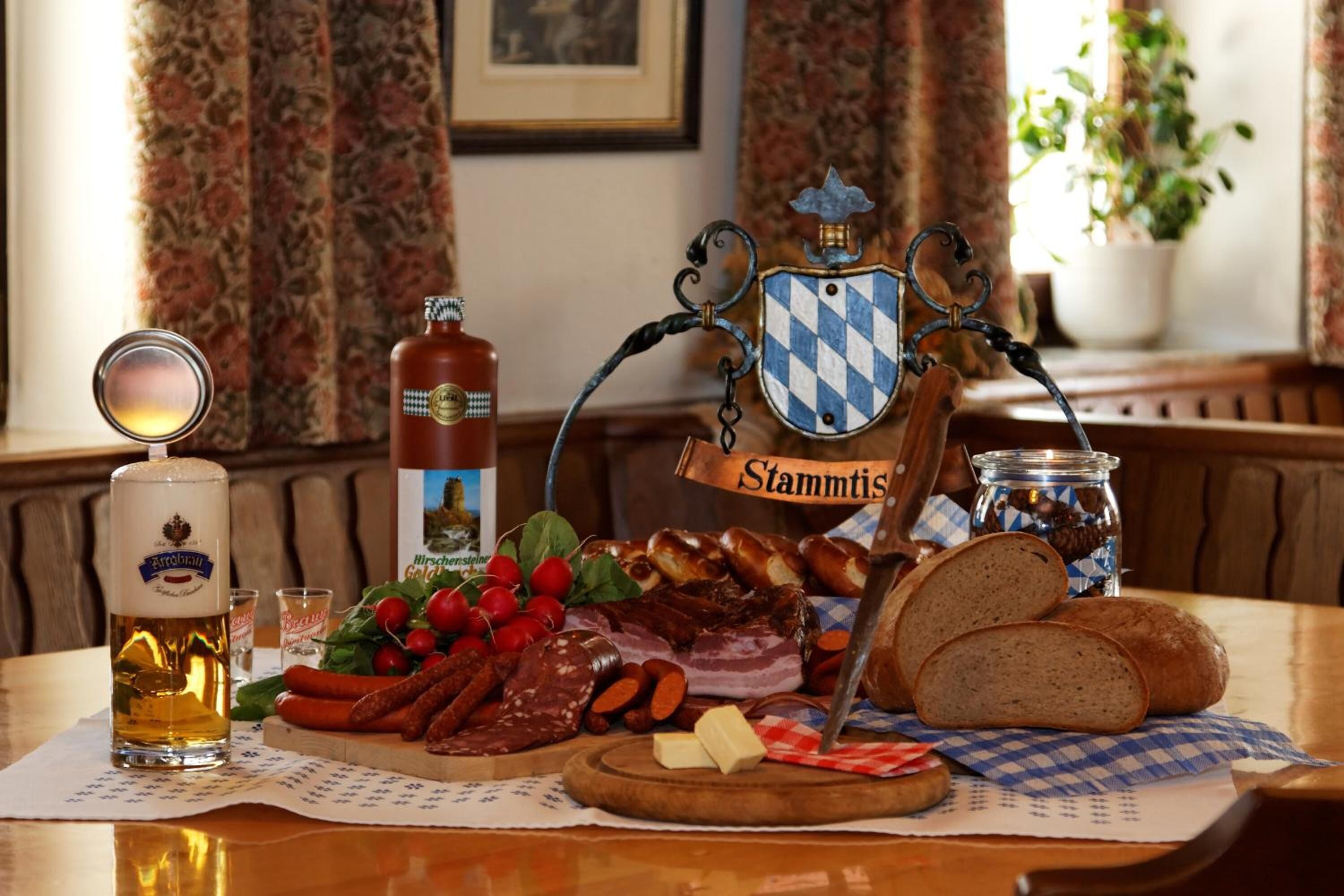 Una mesa con cerveza, una botella de vino, una tabla de quesos y un cartel que dice 'Stammhaus'.