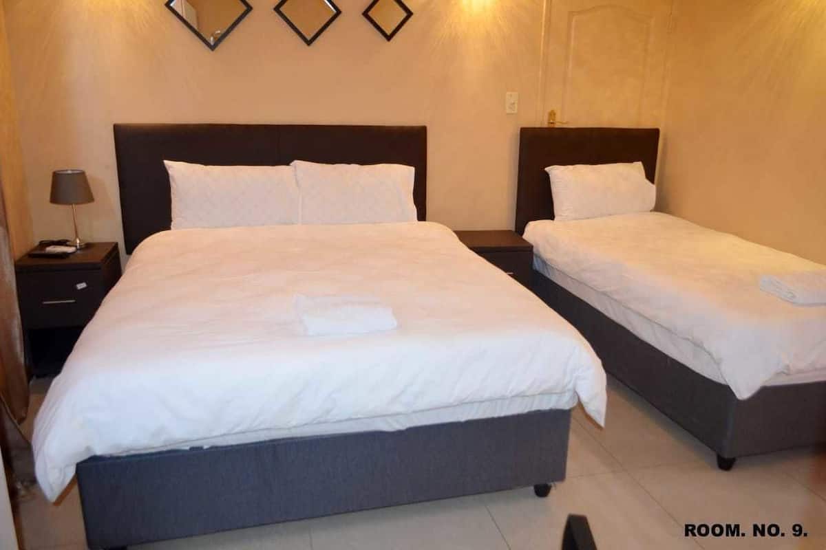 A hotel room with two beds, a nightstand with a lamp, and a mirror on the wall.