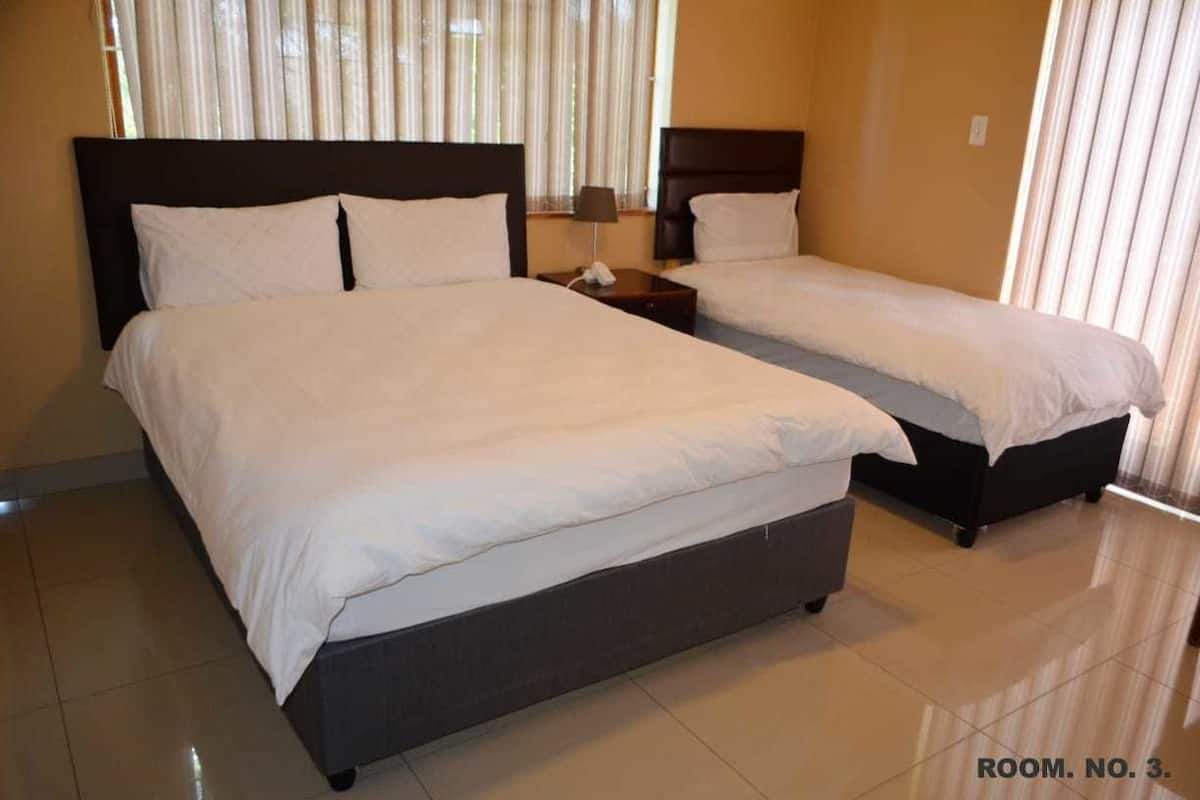 A hotel room with two beds, a nightstand, and a lamp.