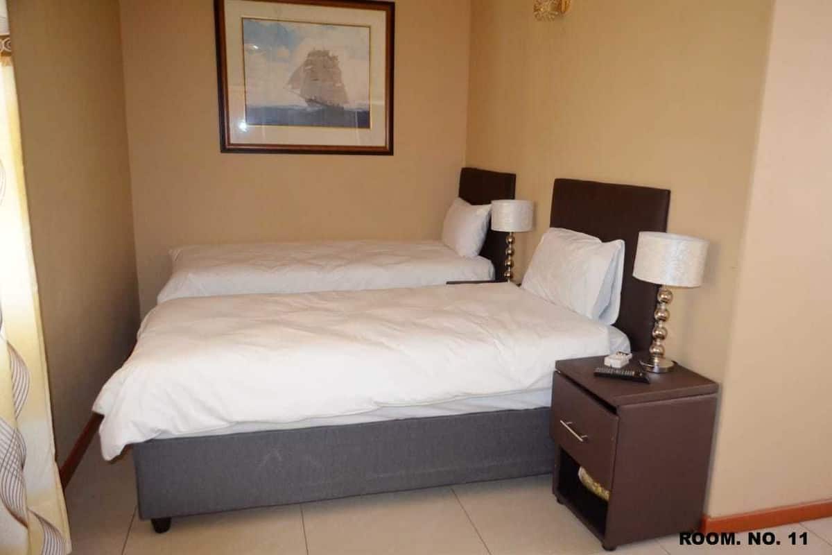 A double bed with two nightstands, a framed picture on the wall, and a room number sign.