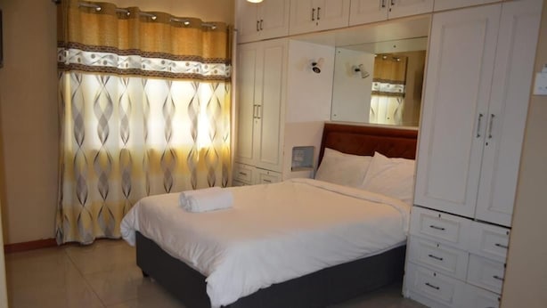 Une chambre à coucher avec un lit, une armoire, un miroir et un rideau.