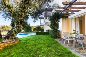 Eine Terrasse mit Tisch und Stühlen, einer Pergola und einem Swimmingpool.