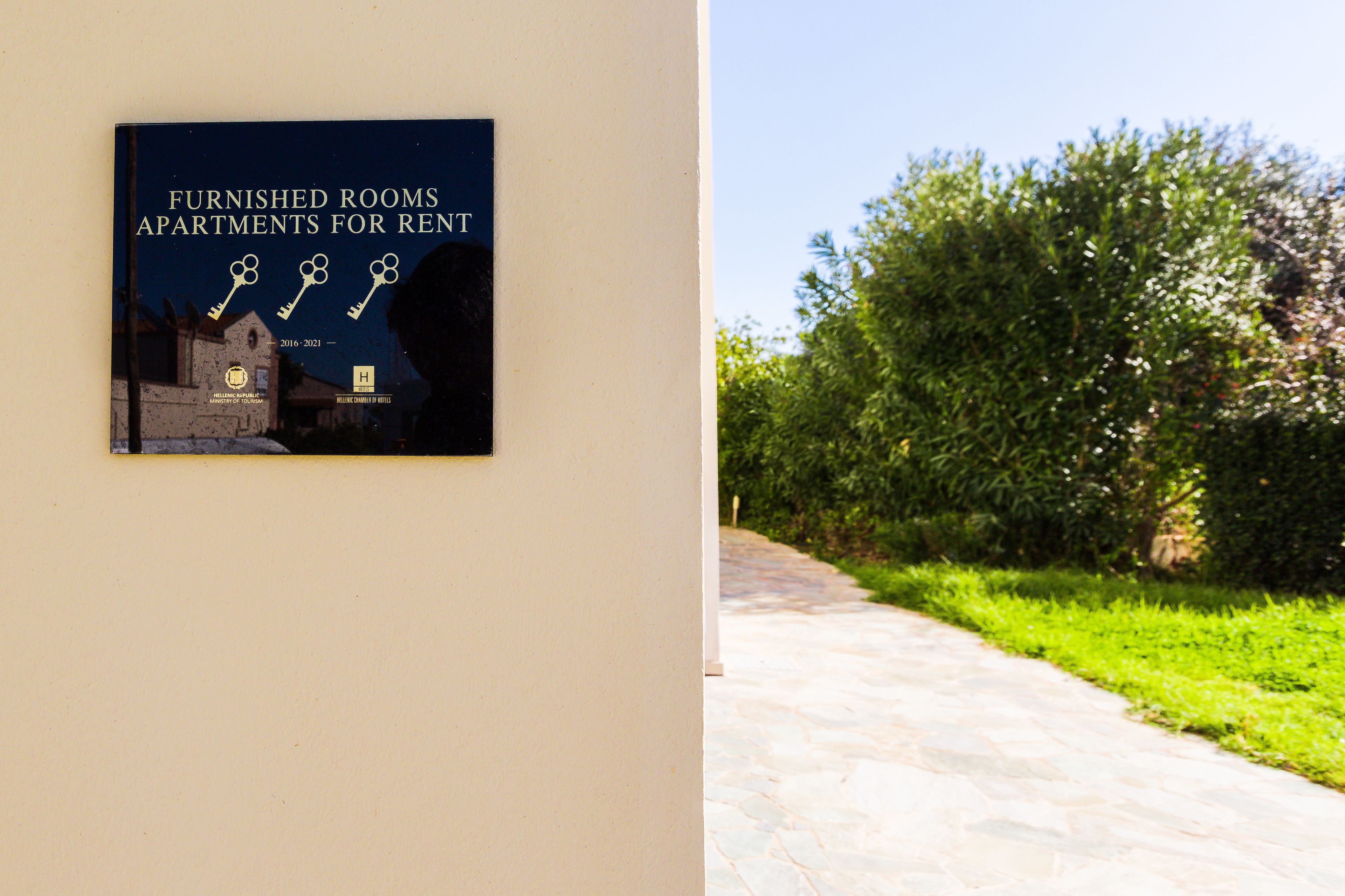 A framed sign on a wall with the text "Furnished Rooms Apartments for Rent" and a key symbol.