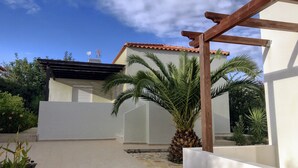 Ein weißes Gebäude mit einem Ziegeldach und einer Holzpergola.